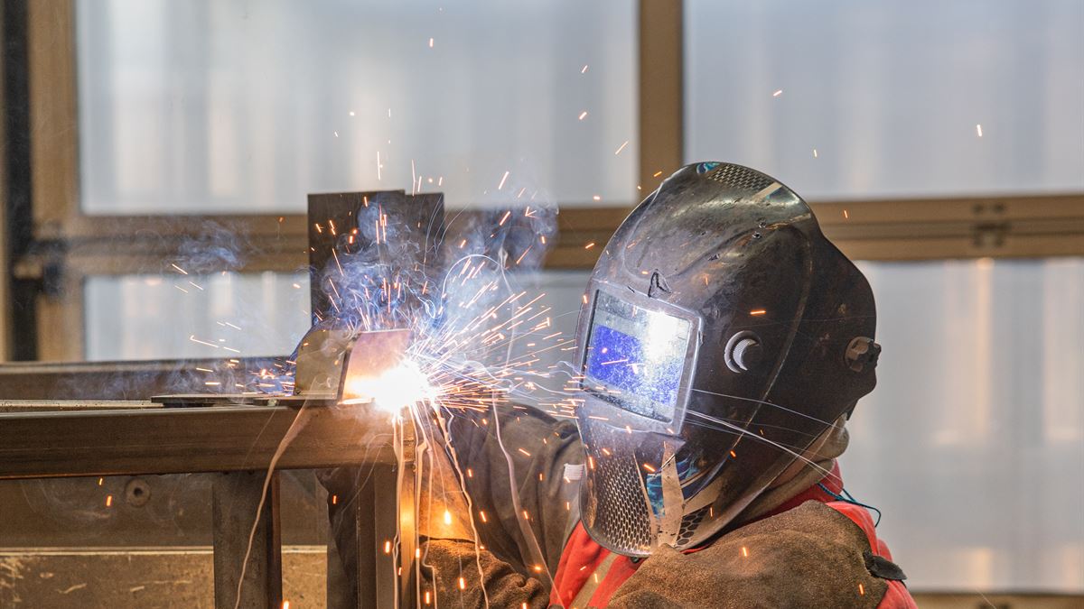 Schweißer von WEICK Maschinenbau schweißt eine Stahlkonstruktion, Funken fliegen
