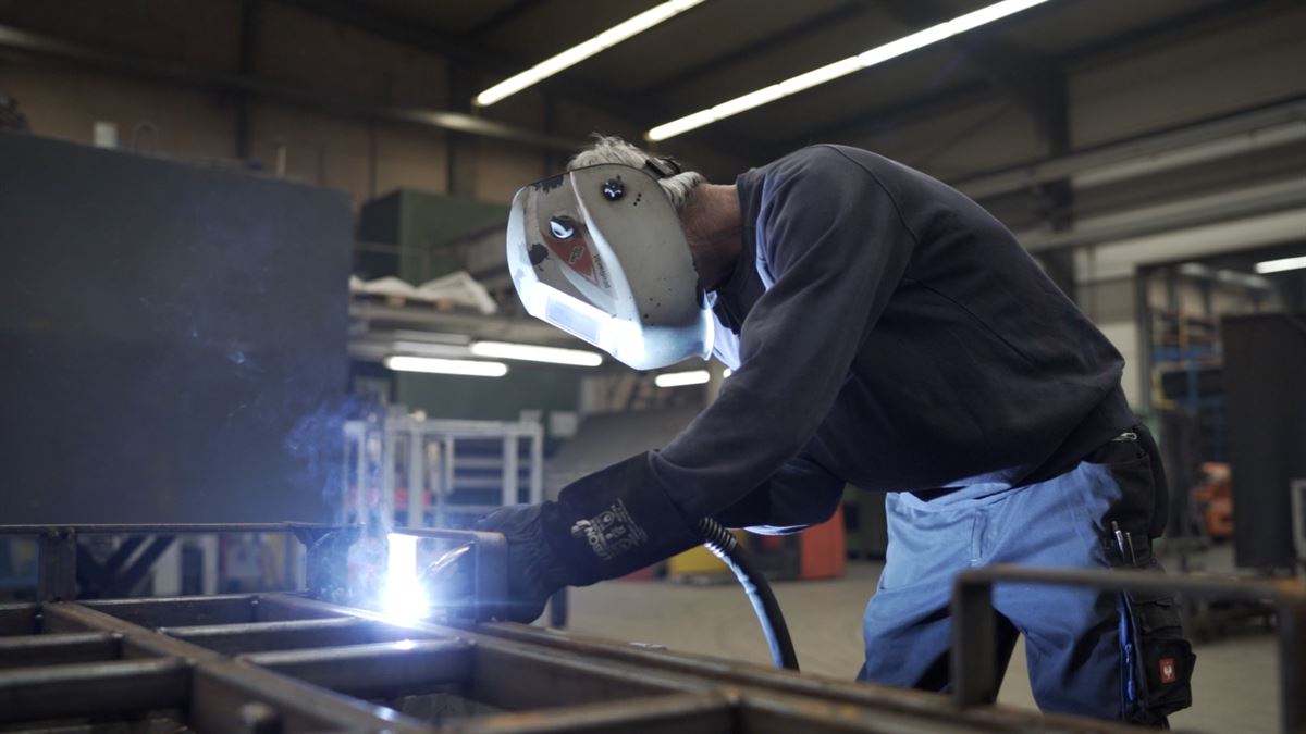 Schlosser von WEICK Maschinenbau schweißt an einer Rahmenkonstruktion in der Produktion